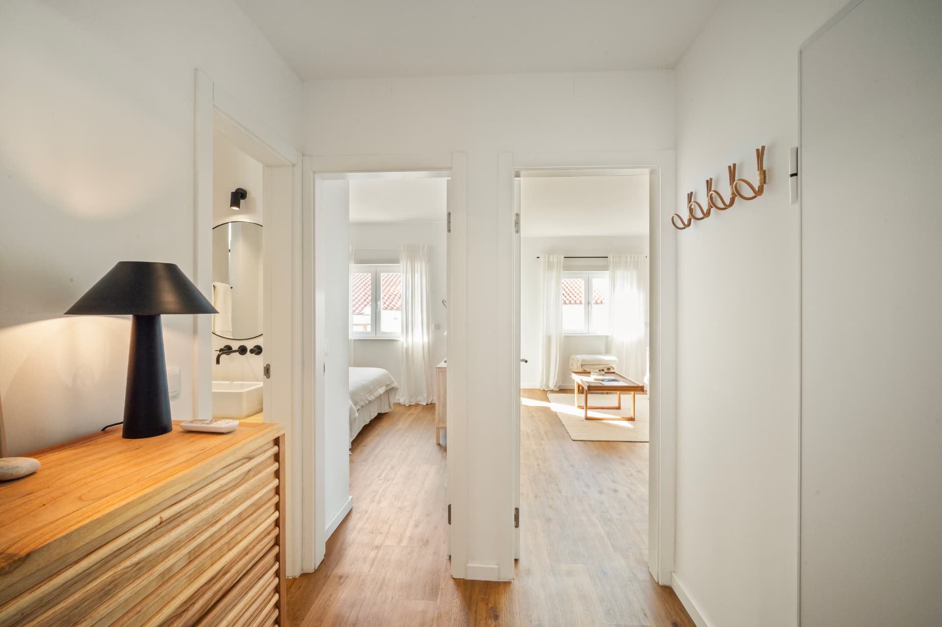 Hallway with rattan coat hooks, looking into the bathroom, a bedroom and the living room