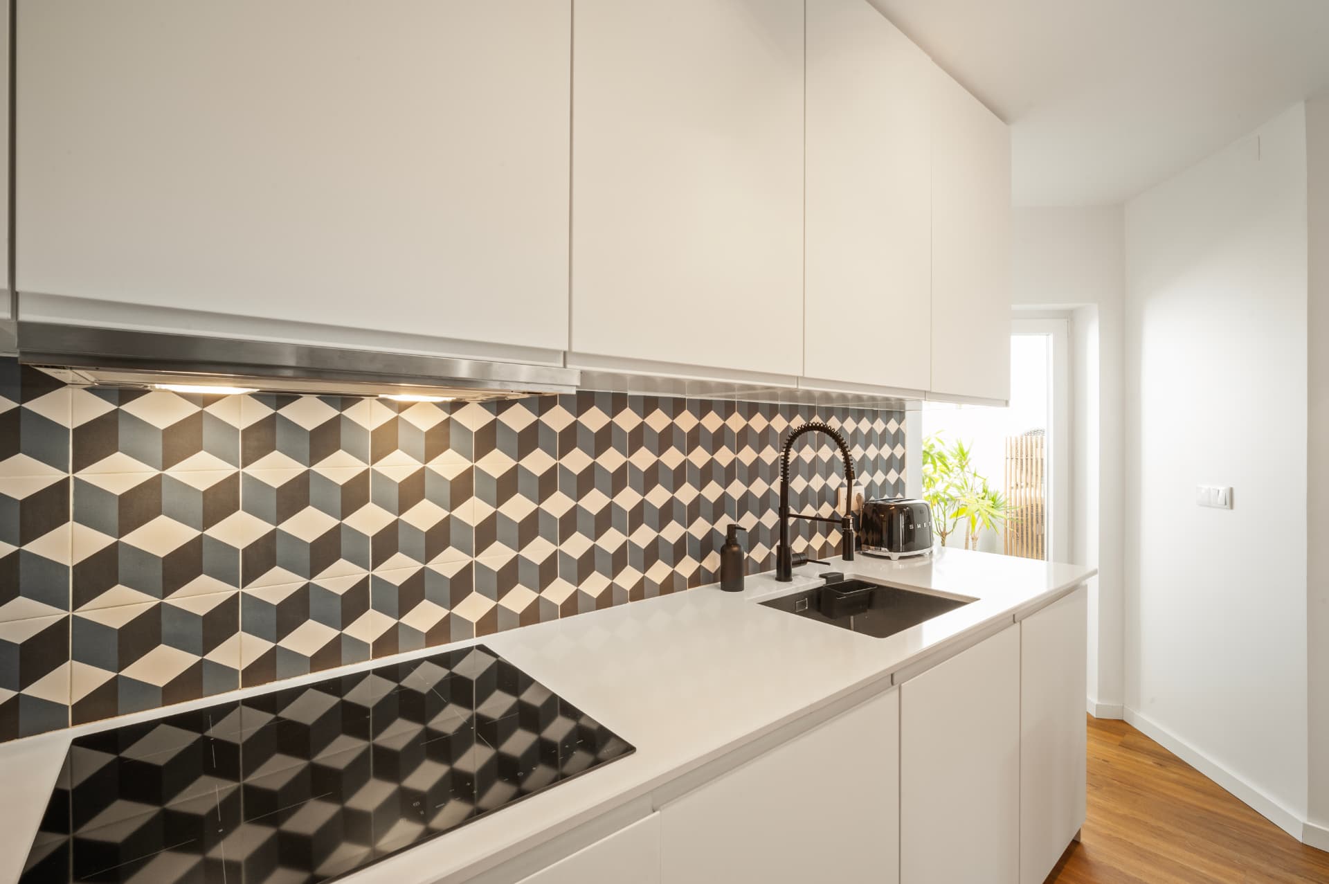 The kitchen: cube-patterned tile backsplash and the hob, with the bright opening to the terrace at the right